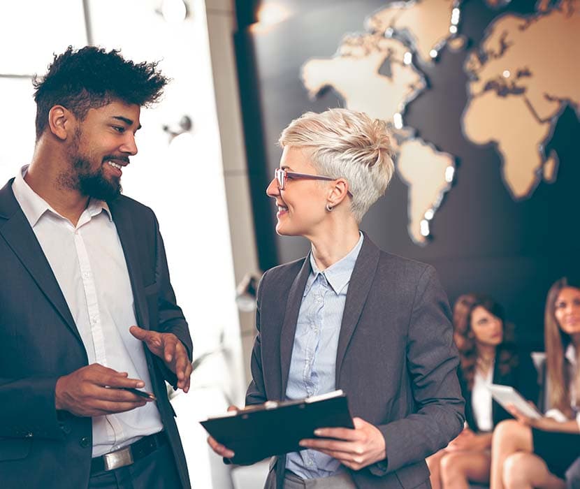 An Asian Indian male and white female talking in the office