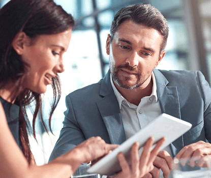 A female co-worker showing her male co-worker something on a tablet device